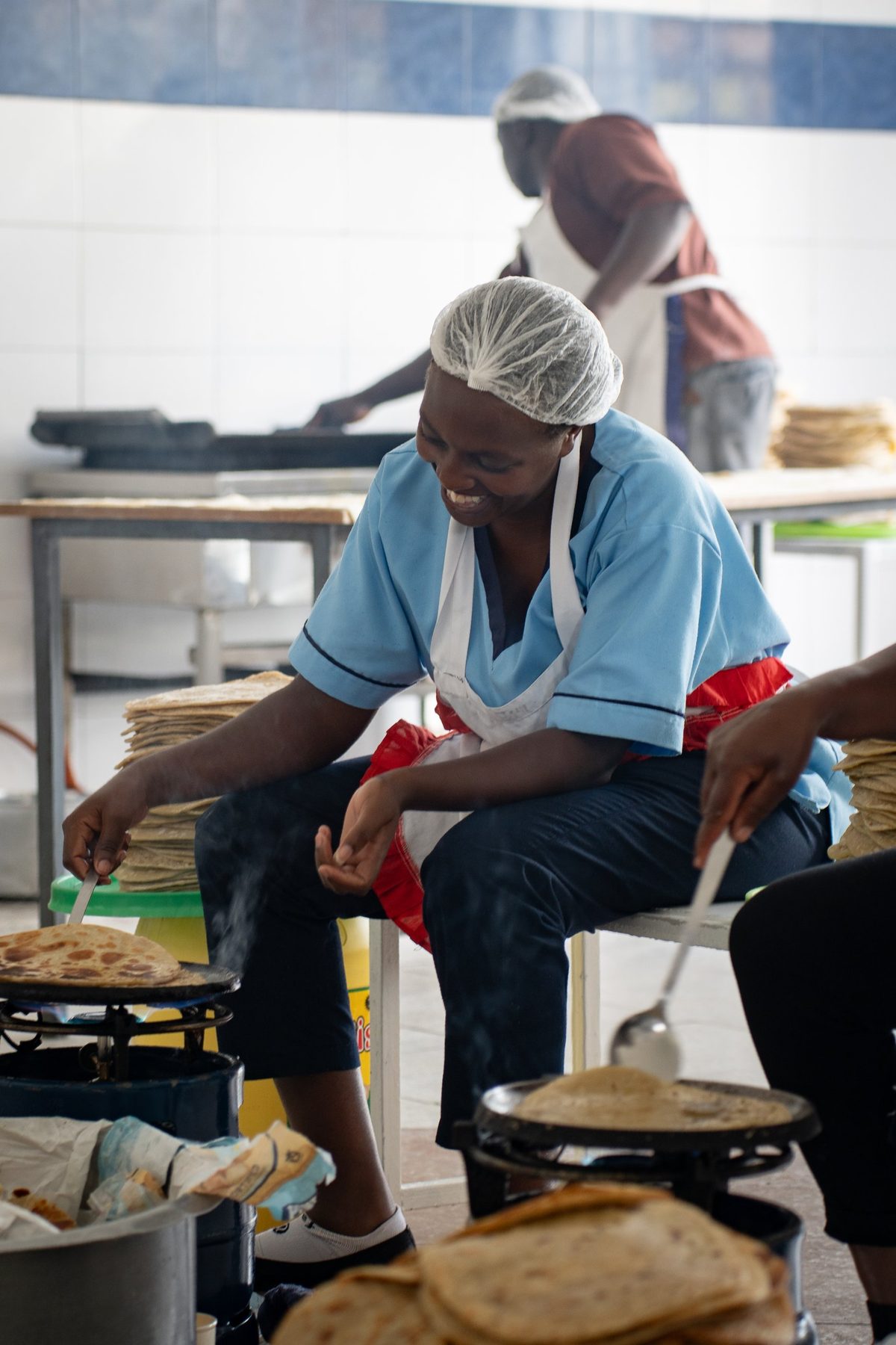 A cook laughing as she turns chapati on the stove