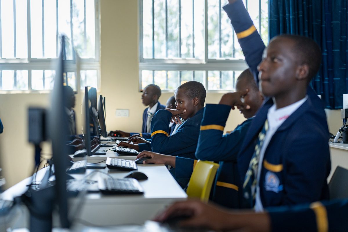A boy with his hand up in the ICT suite